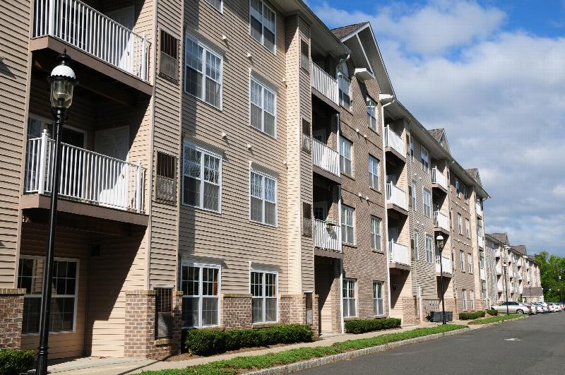 Side view photo of the exterior of Park Terrace apartment building, showing a 4 level building with brick and siding, and many private balconies.