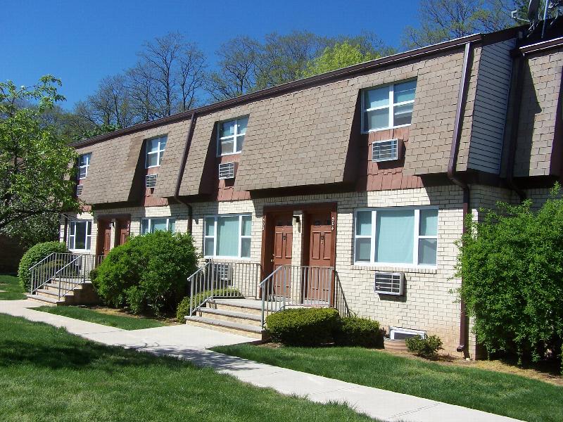 Woodbridge Village exterior photo shows a brick apartment building, green bushes line the front of the building.
