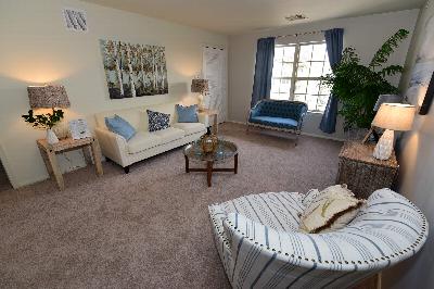 Yorkshire Village community room showing a couch and 4 chairs on hardwood floors. There are 3 closets and a ping pong table. Windows allow natural light to enter the room.