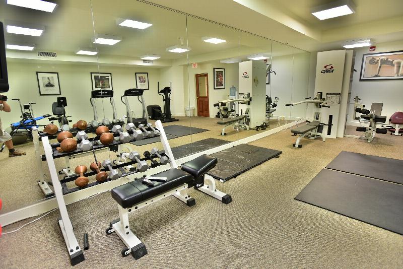 Yorkshire Village gym photo showing a dumbbell set, foam mats, an elliptical, two treadmills and two exercise bikes among other exercise equipment. There are motivational pictures on the wall.