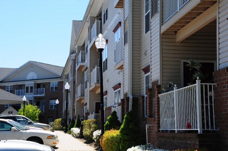Hyde Park Exterior photos showing a vinyl and brick exterior with several balconies. Several lampposts and several bushes and trees highlight the landscape.