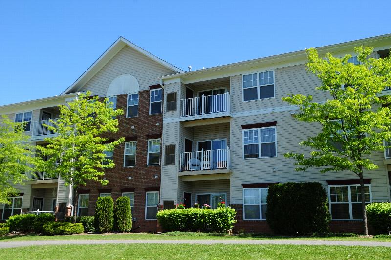 Hyde Park Exterior photos showing a vinyl and brick exterior with several balconies. Several bushes and trees highlight the landscape.