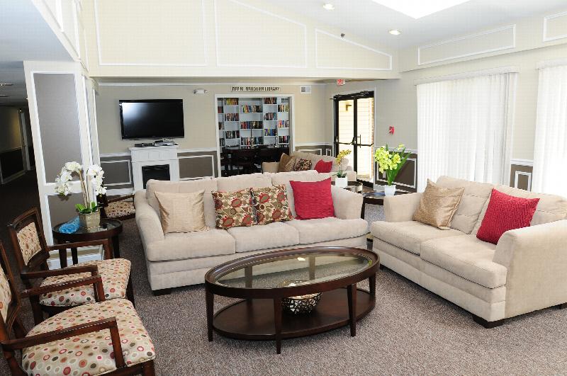 Edison Woods Seniors for ages 55 and over photo of the community room shows a seating area with coff table and a wall mounted TV.