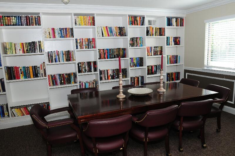Edison Woods Seniors for ages 55 and over shows built in book cases stocked with books and a table with seating for eight.