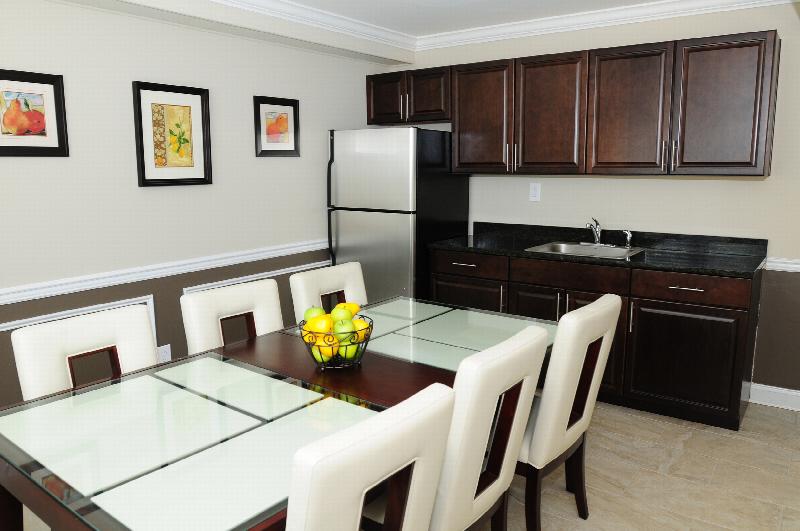 Edison Woods Seniors for ages 55 and over kitchen shows dark cabinets with a granite countertop, stainless steel refrigerator and table with seating for six.