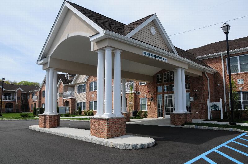 Village at Stratford for ages 55 and above exterior photo showing the covered area at the main entrance for picking up and dropping off tenants.
