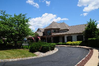 Pike Run Affordable Exterior photo showing the Club House with a sign for Pike Run. Several bushes and trees highlight the landscape.