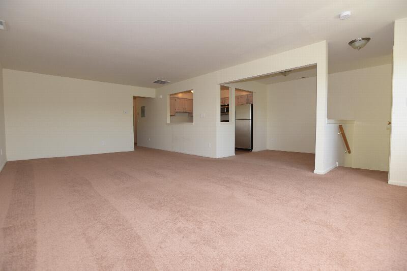 Homestead Village interior photo of the living room area featuring new carpeting and freshly painted walls. Entrance to the kitchen can be seen in the background.