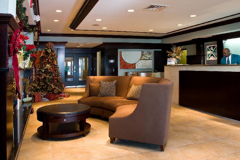 Helix at Xchange Affordable photo of interior lobby entrance showing large couch and round coffee table in front of a marble fire place. A large concierge desk station and attendant can be seen in the back ground.  