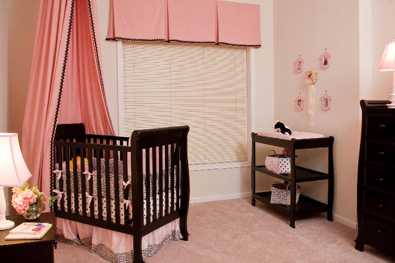 Helix at Xchange Affordable interior photo of bedroom with a crib, changing table and night table. A dresser and large window with valance can be seen in the background.  
