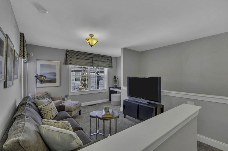 Interior Photo of the model at Princeton Terrace at West Windsor showing the loft area with seating area ant tv, wall to wall carpeting and a double window to allow for natural light. 