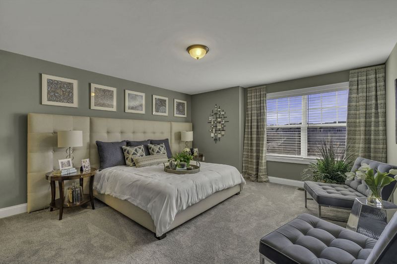 Interior Photo of the model at Princeton Terrace at West Windsor showing a bedroom with bed, night stand and dresser with wall to wall carpeting. Large double window to allow for natural light. 