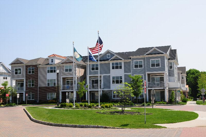 Princeton Terrace at West Windsor Affordable exterior photo showing several balconies and a streetlight. There are 3 flag poles on display. Several bushes and trees highlight the landscape.