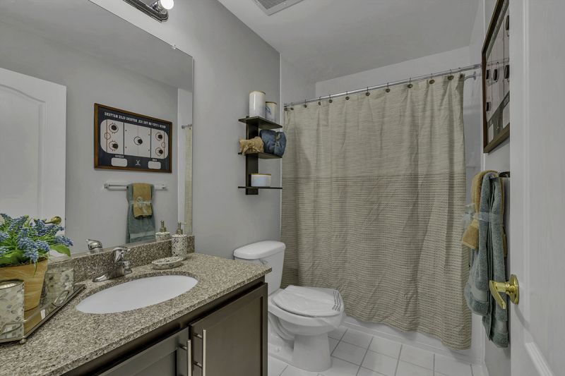 Interior Photo of the model at Princeton Terrace at West Windsor showing a bathroom with tun and shower, toilet and vanity with large mirror