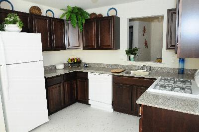 Photo of the kitchen at Harbortown Heights showing dark cherry cabinets, granite countertops and new appliances.
