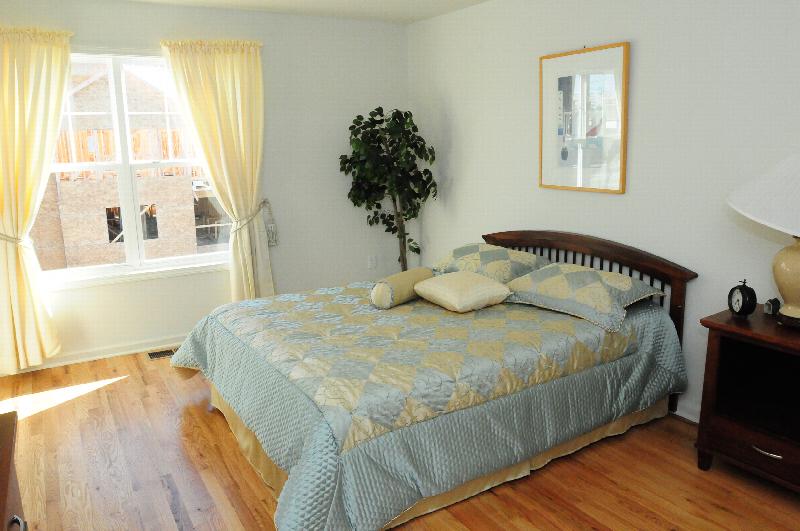 Harbortown Heights bedroom photo shows a queen sized bed with a dresser. The room features a window and hardwood floors.