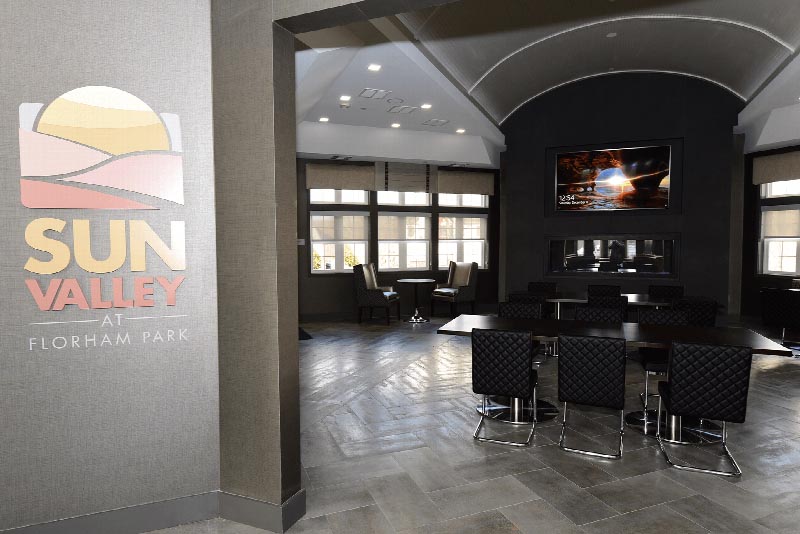 Photo of the entranceway to the community room at the Summit Club at Sun Valley. Several seating areas are shown as well as a wall mounted TV above a fireplace.