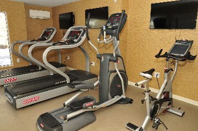 Autumn Hills fitness center photo shows an exercise bike, an elliptical and two treadmills. Three flat screen TVs are on the wall