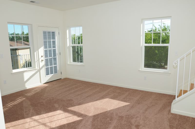 Colonial Heights living room shows new carpeting, a door leading to an exterior balcony, and interior stairs leading to the upper level.