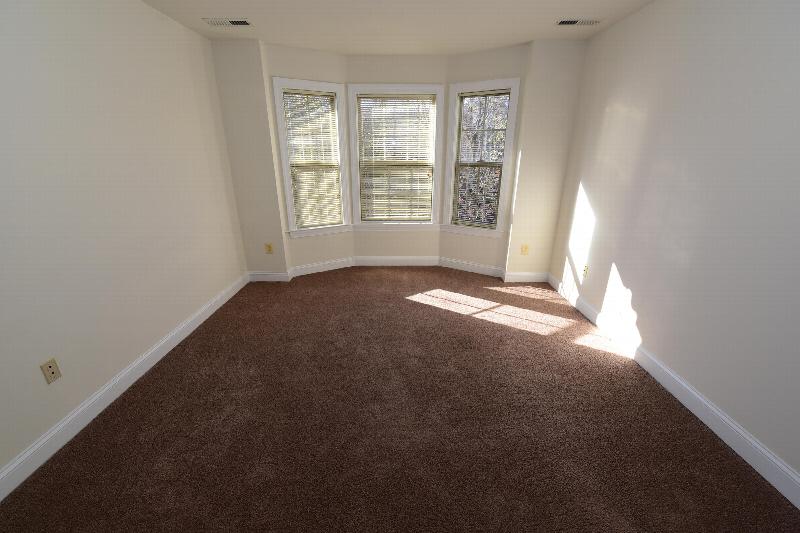 Pike Run Village interior photo showing a renovated bedroom with new carpeting and paint. There is a large bay window to let in natural light.