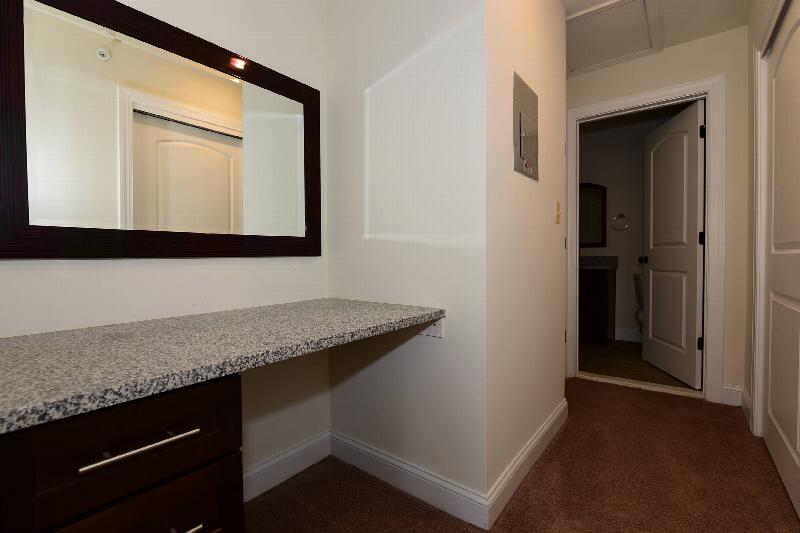 Pike Run Village interior photo showing a changing area with wall mirror, granite counter top and drawers for storage below. There is a short hallway leading to a bathroom.