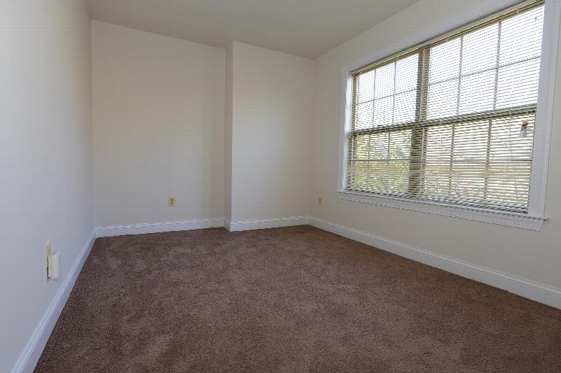 Pike Run Village interior photo showing a renovated den with new carpeting and paint. There is a large bay window to let in natural light.
