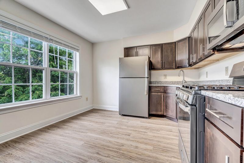 Interior photo of a renovated apartment at Pike Run Village, showing a renovated kitchen with wood grain flooring, new kitchen cabinets countertop and appliances. 