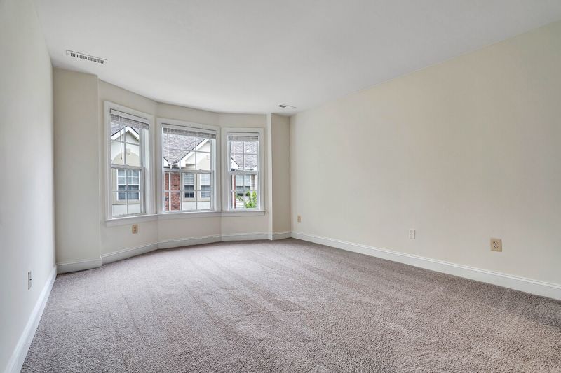 Interior photo of a renovated apartment at Pike Run Village, showing a bedroom with new carpet, paint and a large window for natural light.