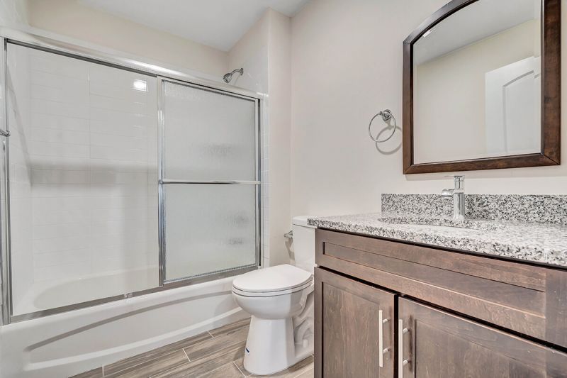 Interior photo of the Pike Run Community Clubhouse, showing the community lounge area, with multiple seating areas in front of a fireplace, with large windows looking out on the grounds.