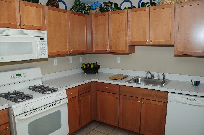 Harbortown Sail interior photo of the kitchen showing maple colored cabinets, a white countertop and white appliances.