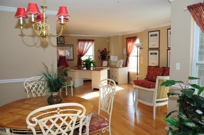 Photo of living space inside a Harbortown Sail apartment. Hardwood floors fill the room. There is dining area with a table for 4, and a desk can be seen in the background.