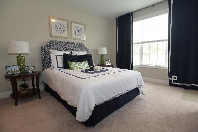 Woodhaven Commons bedroom photo features a queen sized bed, two end tables with lamps. There is a large window that lets in natural light, decorated with window treatments.