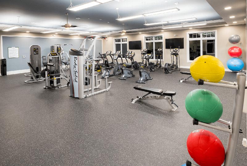 Gardens at Jackson Twenty One Clubhouse photo showing the exercise room containing three treadmills, three ellipticals, and three exercise bikes along with various other exercise equipment.