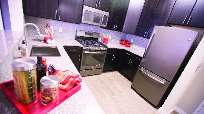 The Grove at One92 Kitchen photo showing espresso cabinets, stainless steel appliances and laminate flooring. There are several decorations on the kitchen counter.