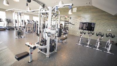 The Grove at One92 Gym photo showing four treadmills, three exercise bikes and various exercise equipment. There are large windows that allow natural light to enter the room.