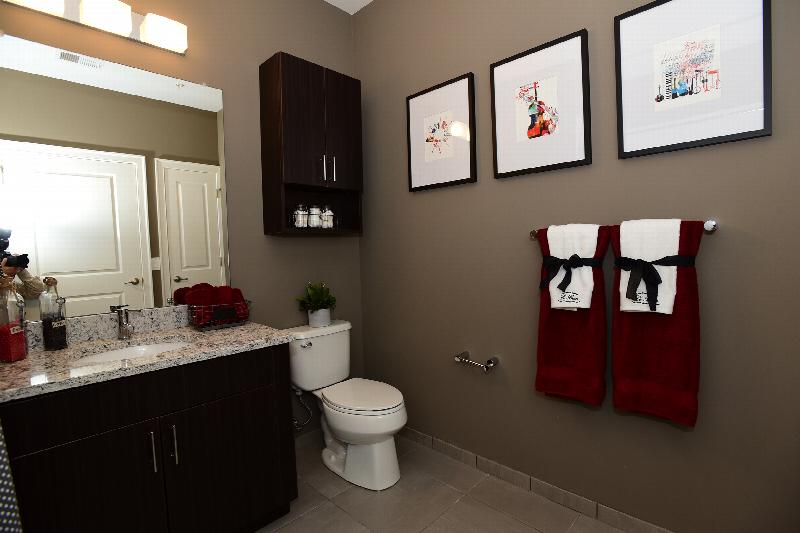 Station Village at Avenel photo of half bathroom shows a vanity with grainite countertop, sink with a mirror above and a toilet.