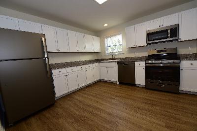 Pike Run Meadows photo of the revised kitchen showing new cabinets, granite countertops, stainless steel appliances and wood grain tile flooring.