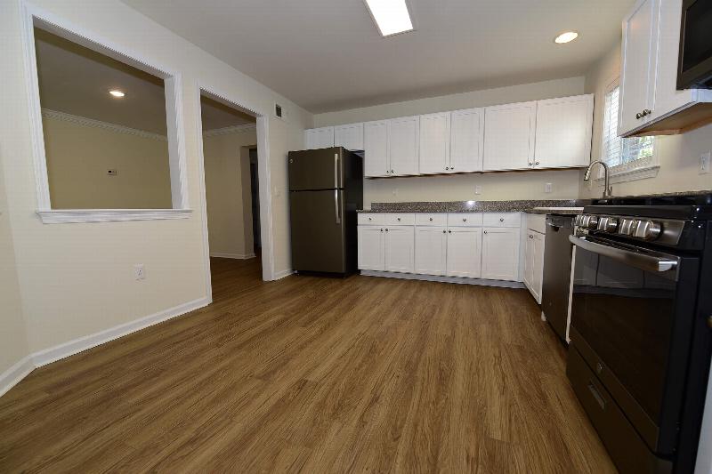 Pike Run Meadows interior photo showing a renovated apartment kitchen with new cabinets, granite countertops, stainless steel appliances and wood grain flooring.