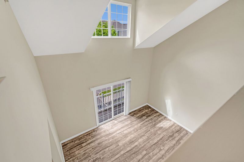 Interior photo of a renovated apartment at Pike Run Meadows, showing the view from the second floor loft into the dining area. Sliding glass doors lead to a balcony.